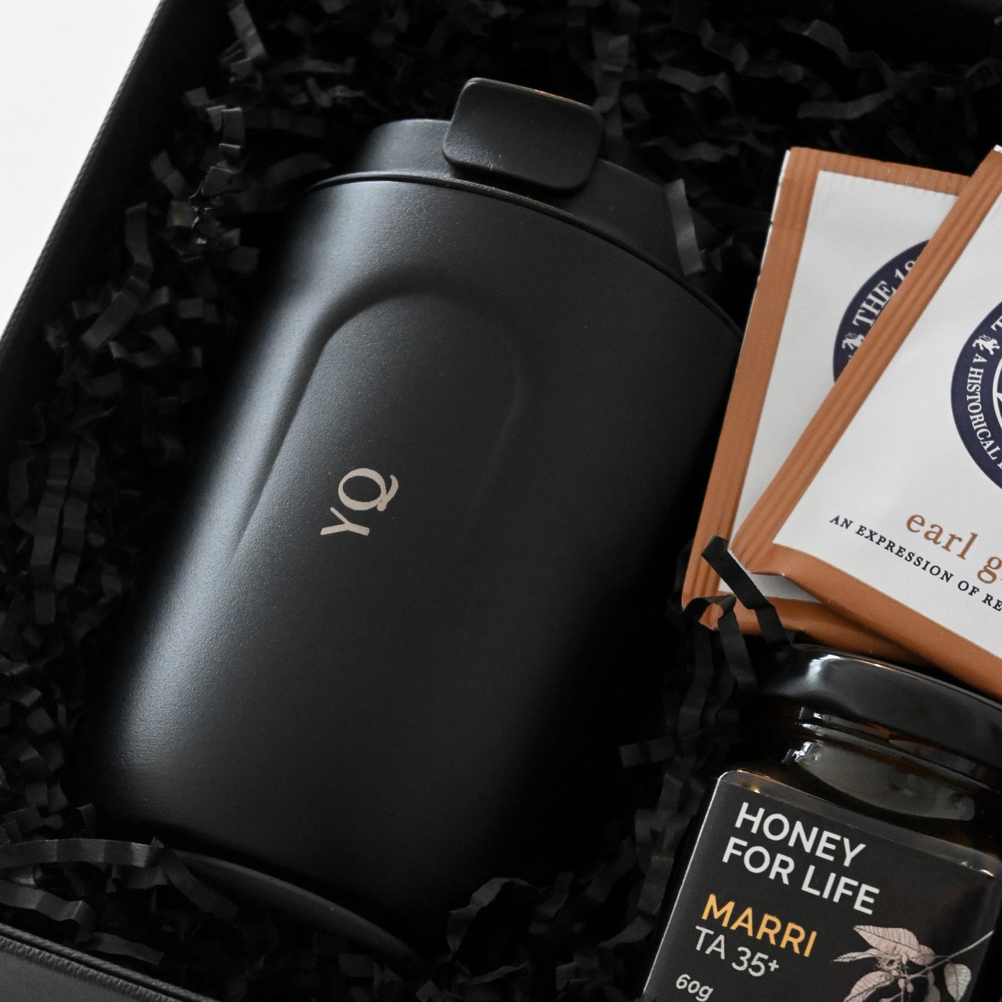 Gift set with a black personalised tumbler, tea bags, and honey in a black box