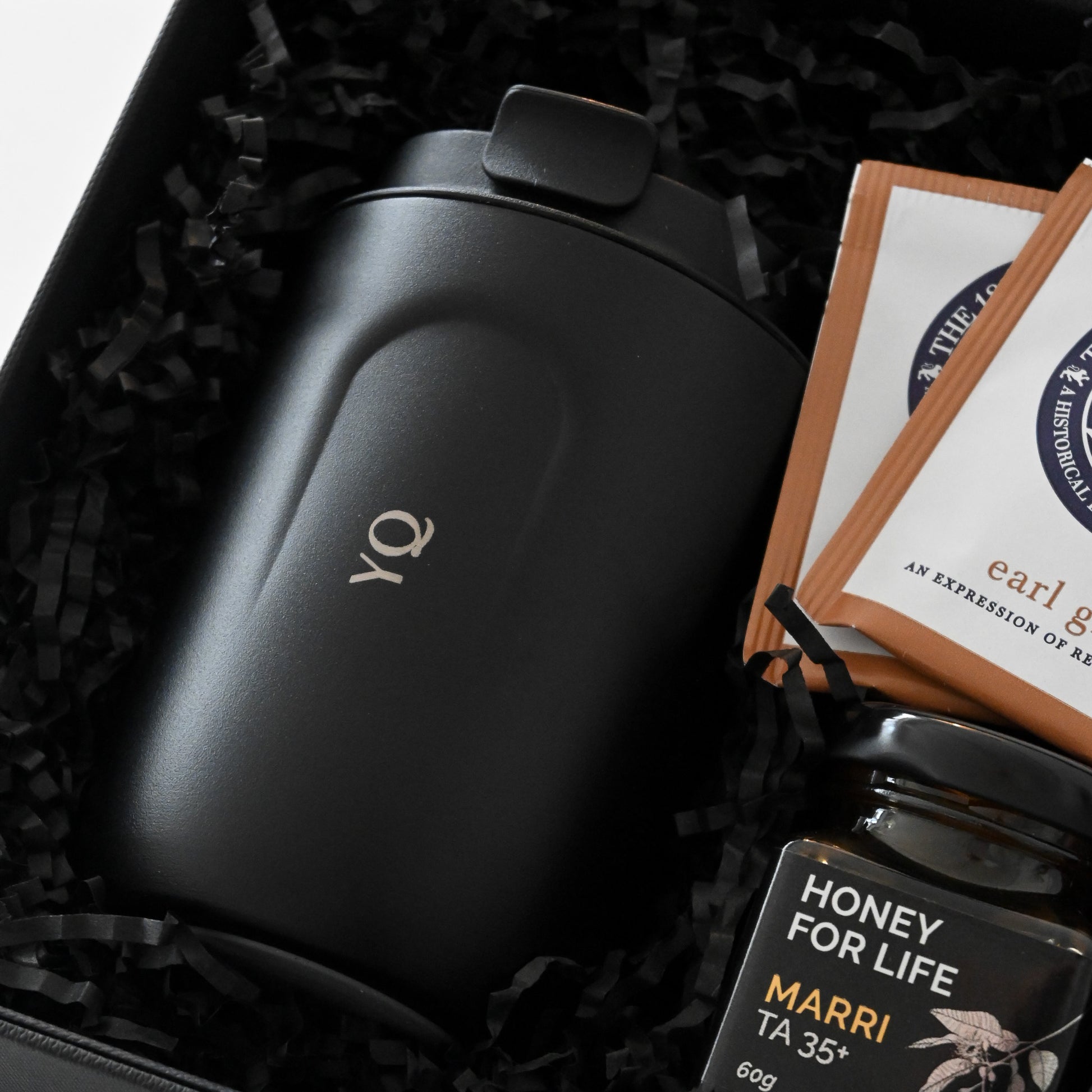Gift set with a black personalised tumbler, tea bags, and honey in a black box